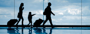 Sihouette of young family with luggage walking at airport, girl pointing at the window